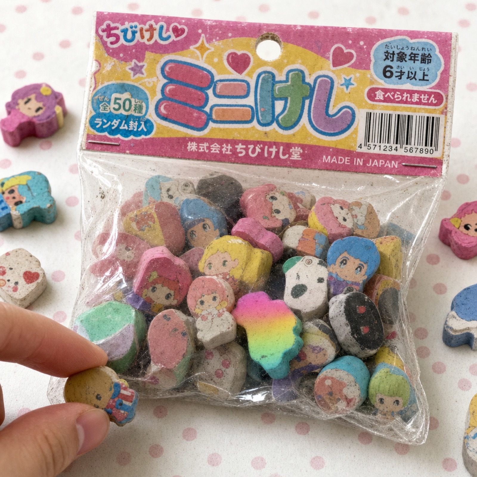 透明な袋に入った、たくさんのミニ消しゴム。指先が1つをつまもうとしている。